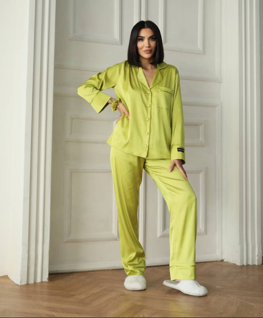 Woman wearing a bright green pajama set standing in a doorway.
